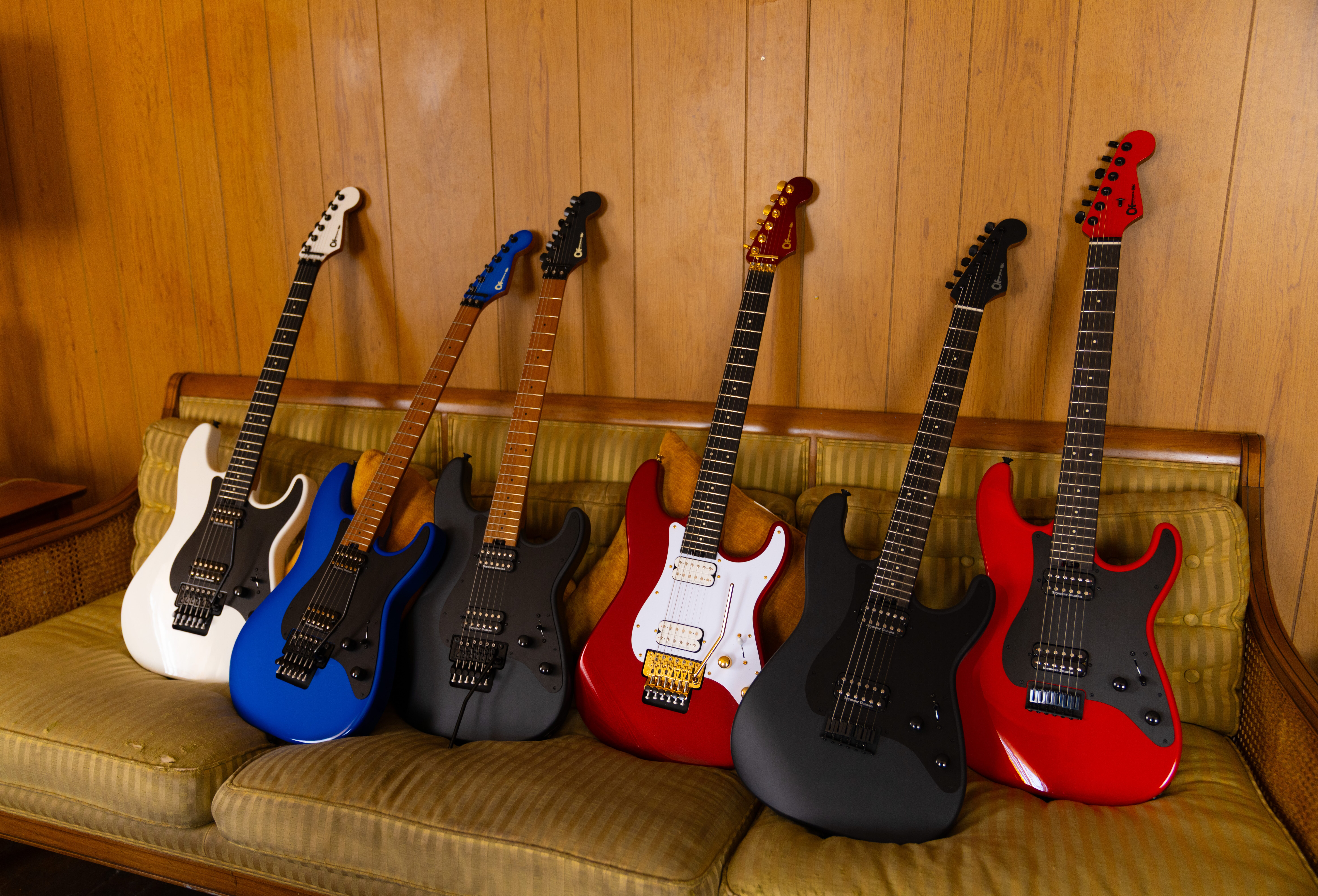 Five Charvel Pro-Mod Plus guitars in different finishes lined up on a couch